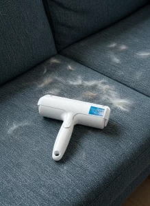 Chom Chom roller removing white cat hair from a grey velvet sofa